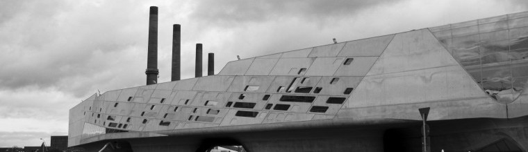 Zaha Hadid's (2005) Phaeno Science Center, in front of smoke stacks of the Volkswagen power plant